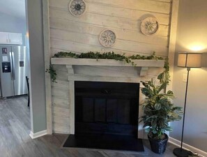 Een moderne woonkamer met een open haard, een koelkast en een potplant.