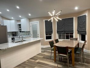 Enjoy meals in the kitchen with a central island and dining area featuring a wooden table and pendant light.