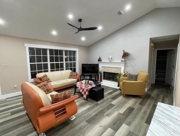 Relax by the fireplace in this inviting living room with a large window and comfortable seating area.