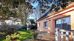 Ein Haus mit Garage, einer Terrasse mit Topfpflanzen und einem Baum im Vordergrund.
