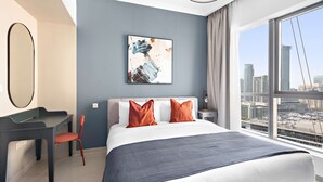 Een moderne hotelkamer met een groot bed, een bureau en een stoel. Er is uitzicht op de stad vanuit het raam.