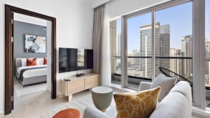 Een moderne hotelkamer met een groot raam, een bed, een televisie, een bank en een kleine tafel.