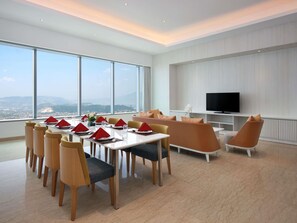 A modern hotel room with a dining area, a sofa, and a TV. - Grand Mercure Lampung (Bandar Lampung)