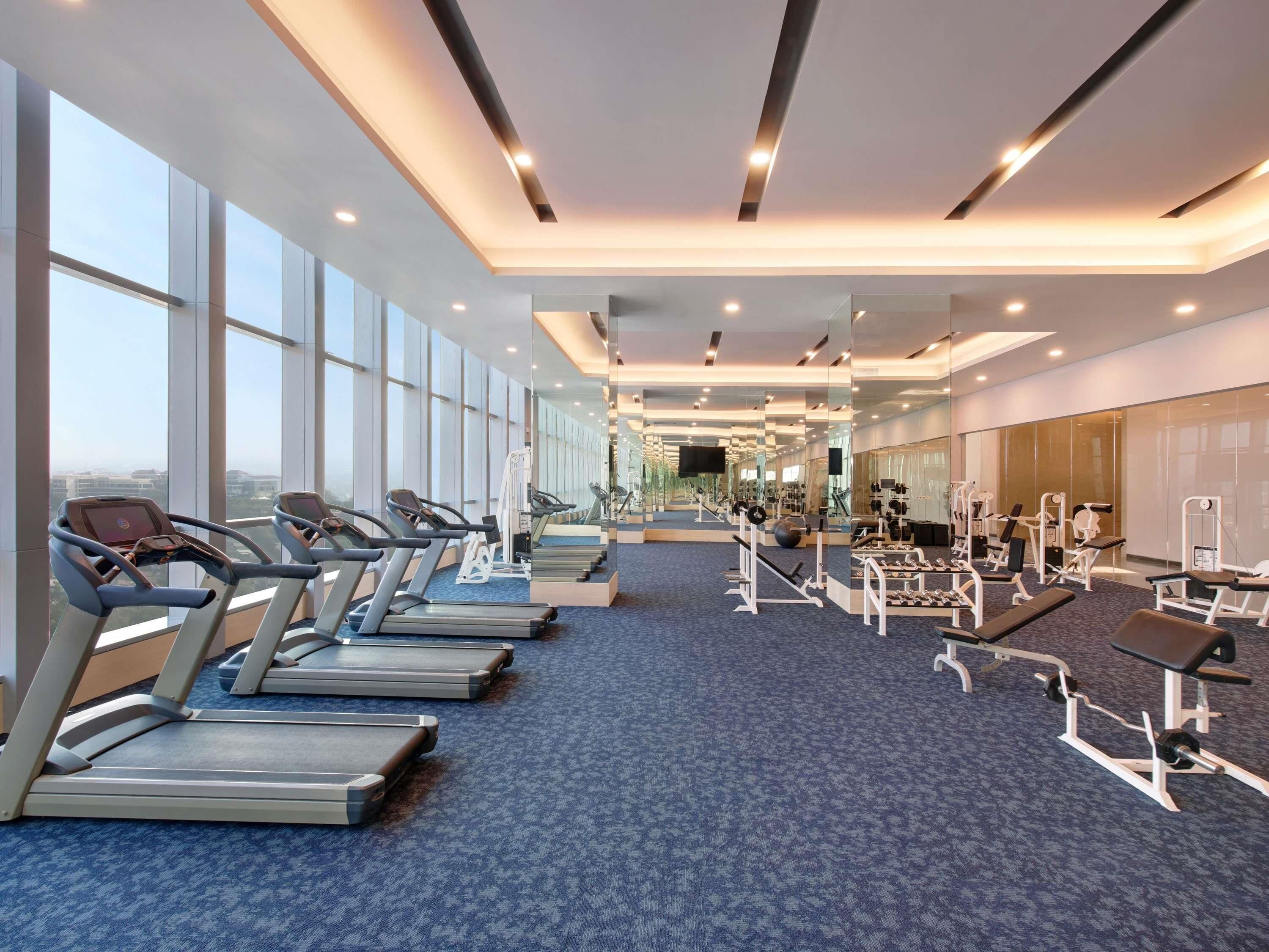 Un gimnasio moderno con cintas de correr, máquinas de pesas y colchonetas de ejercicio.