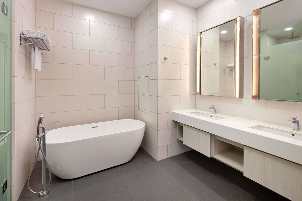 A modern bathroom with a freestanding bathtub, a large mirror, and a vanity with a sink.