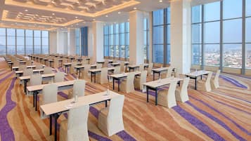 A conference room with multiple tables and chairs, large windows, and a patterned carpet.