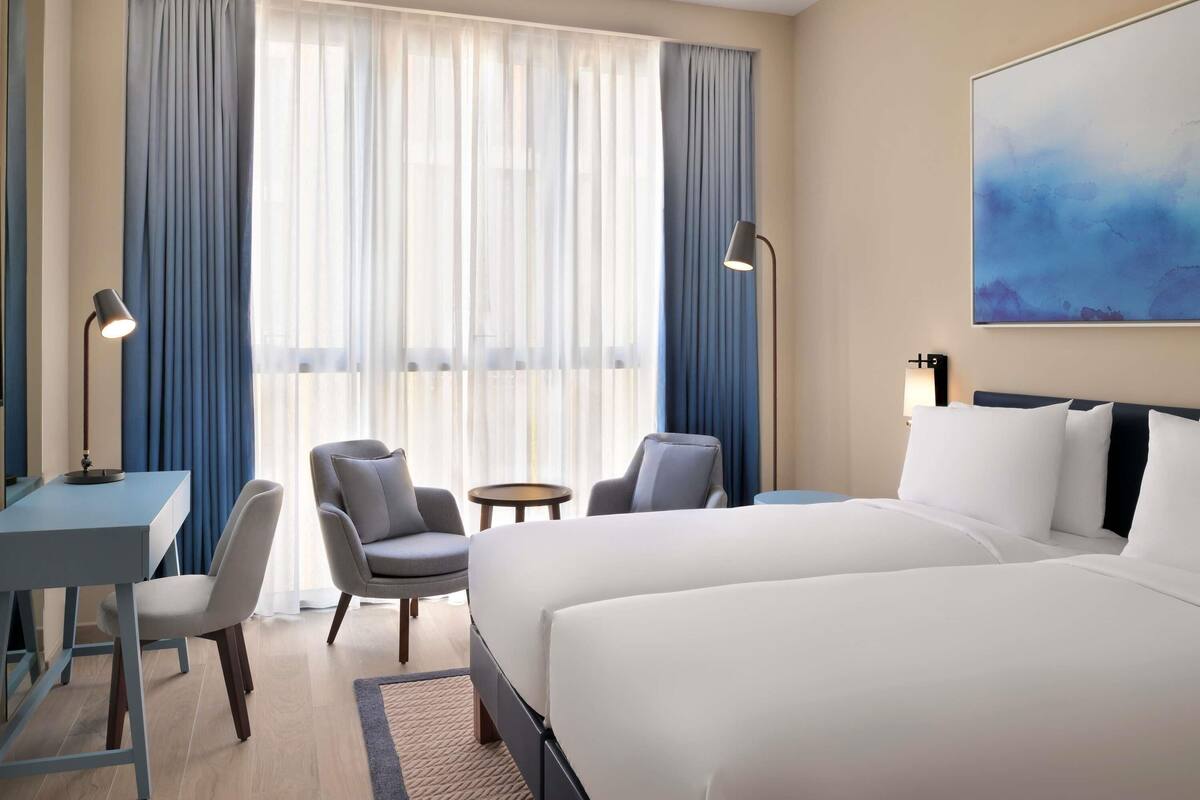 Une chambre d’hôtel avec un grand lit, deux fauteuils, un bureau et une petite table.