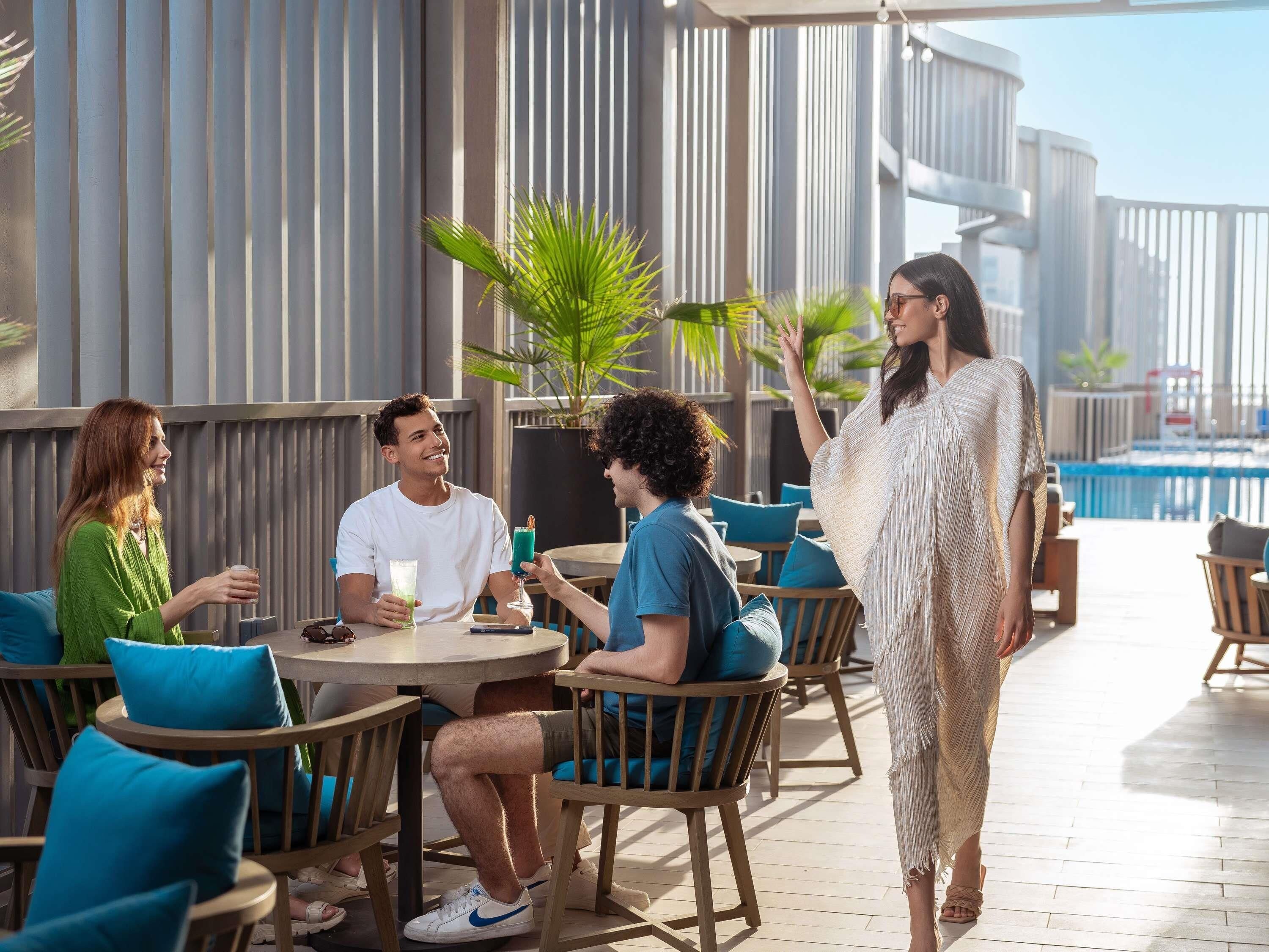 Um bar no terraço com mesas ao ar livre, piscina e arquitetura moderna.