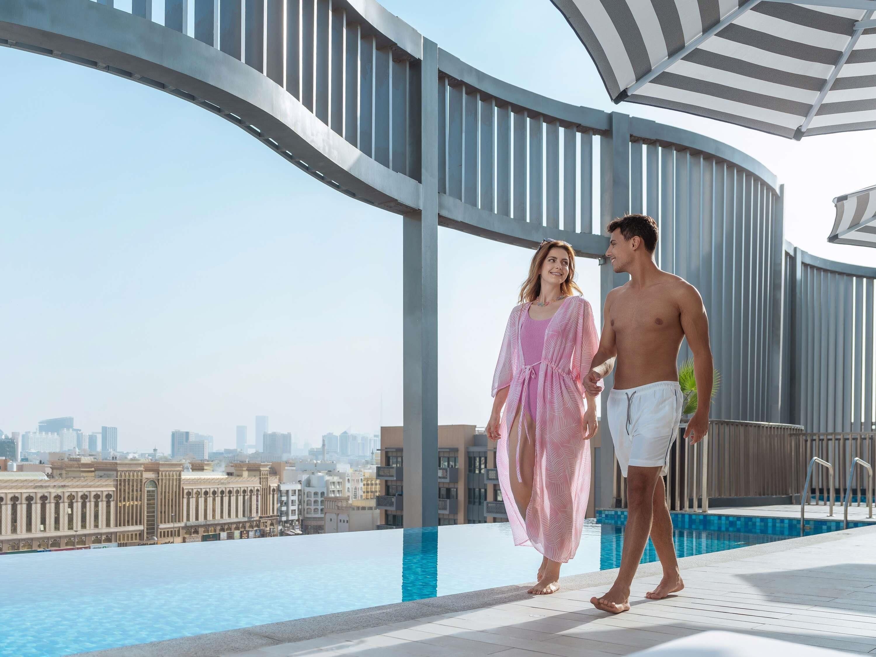 A rooftop pool area with a view of the city skyline, a curved railing, and a clear sky.