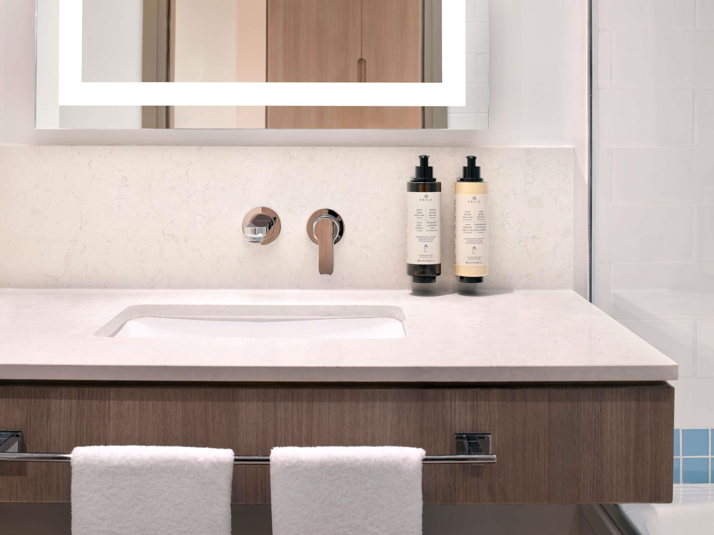 A bathroom with a white sink, two faucets, and two bottles of shampoo and conditioner.