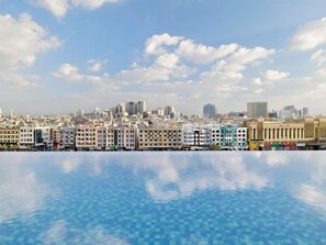 Une vue sur une ville, avec un ciel dégagé et une piscine au premier plan.