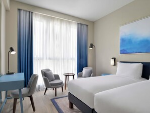 A hotel room with a bed, two chairs, a desk, a lamp, and a painting on the wall. - Mercure Dubai Deira (Dubai)