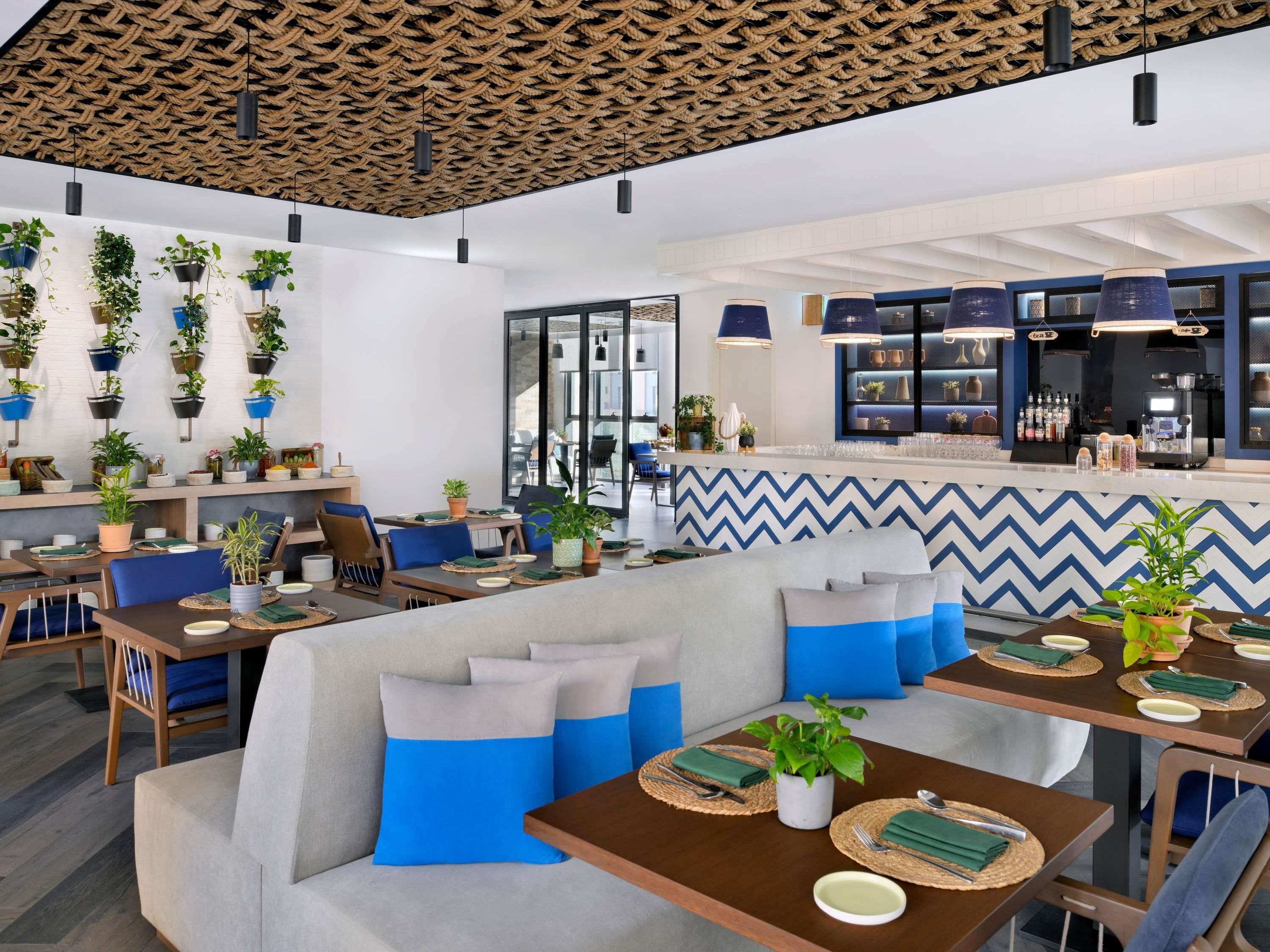 A modern cafe with wooden ceiling, blue and white chevron wall design, and multiple seating areas with tables and chairs.