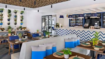 A modern cafe with wooden ceiling, blue and white chevron wall design, and multiple seating areas with tables and chairs.