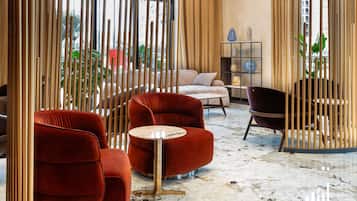 Un interior moderno con sillones de terciopelo rojo, suelo de mármol y vistas de la ciudad a través de amplios ventanales.