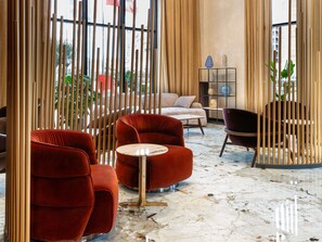 A modern interior with red velvet armchairs, a marble floor, and a view of the city through large windows. - Mercure Tirana (Tirana)