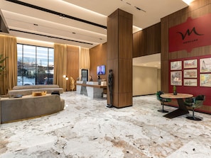 A modern hotel lobby with a reception desk, seating area, and artwork on the walls. - Mercure Tirana (Tirana)