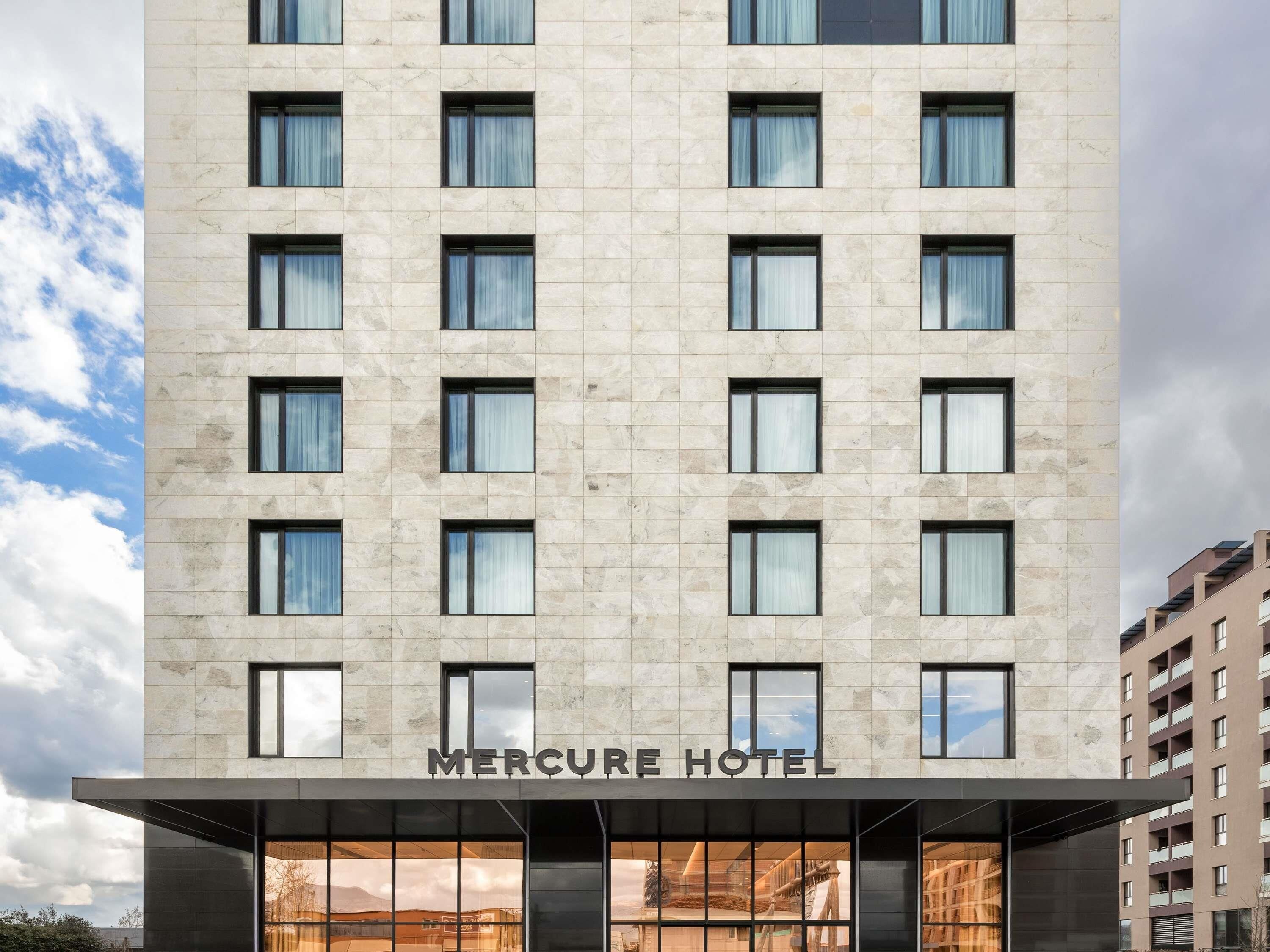 A modern hotel building with a name sign, multiple windows, and a clear sky.