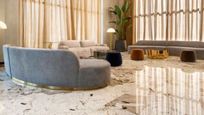 A modern living room with a grey sofa, a round coffee table, and a large potted plant. - Mercure Tirana (Tirana)