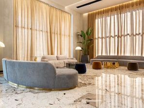 A modern living room with a grey sofa, a round coffee table, and a large potted plant.