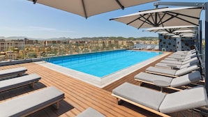 A rooftop pool with lounge chairs and umbrellas, overlooking a cityscape. - Mercure Tirana (Tirana)