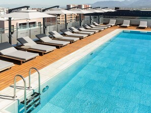 A rooftop pool with lounge chairs and umbrellas, a clear blue pool, and a cityscape view. - Mercure Tirana (Tirana)