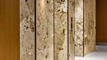 Un pasillo con paredes de mármol y un panel de madera a la izquierda.