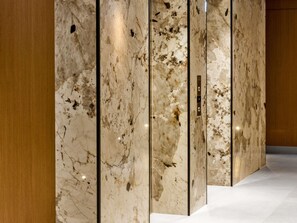 A corridor with marble walls and a wooden panel on the left. - Mercure Tirana (Tirana)