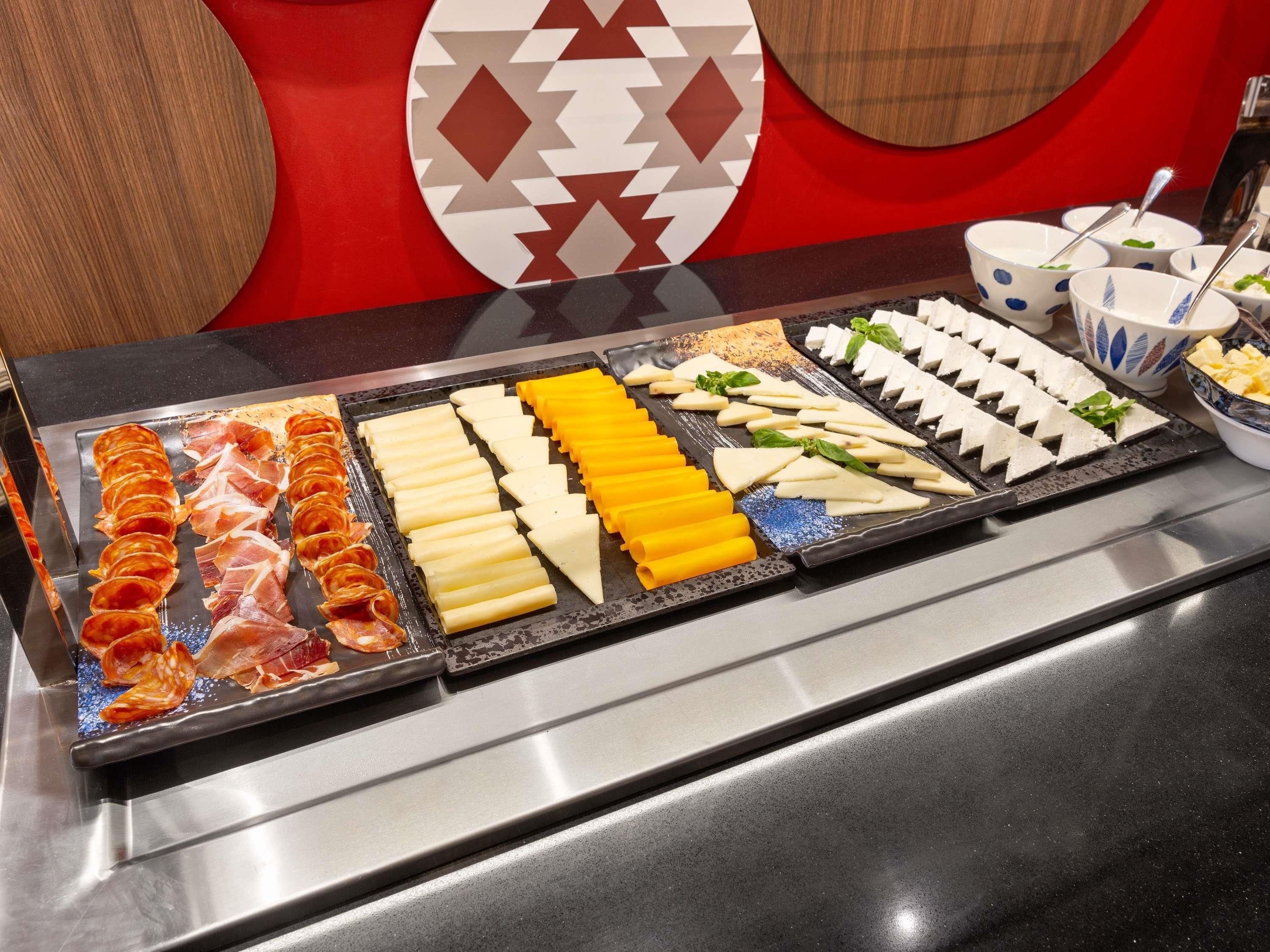 A buffet with various food items including meats, cheeses, and vegetables.
