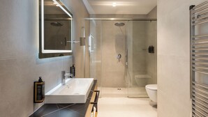 A modern bathroom with a glass-enclosed shower, a white sink, and a large mirror. - Mercure Tirana (Tirana)