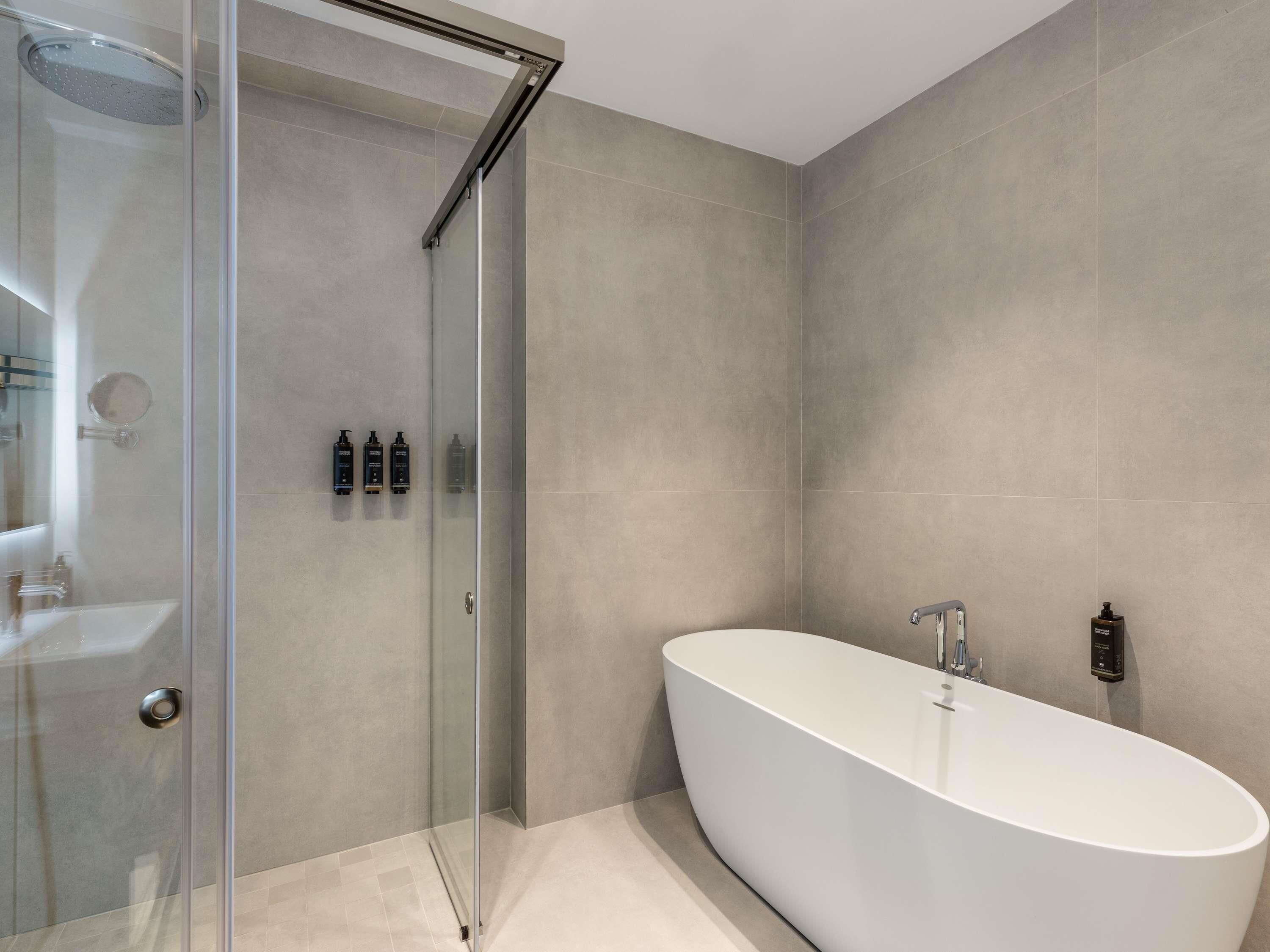 Ein modernes Badezimmer mit einer Glastrennwand-Dusche, einer freistehenden Badewanne und einem minimalistischen Design.