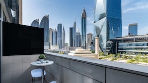 A modern urban balcony with a cityscape view, featuring contemporary buildings and a small seating area with a table and chairs. - Silkhaus Balcony With Great View Studio In Difc (Dubai)