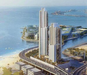 Un ensemble d’immeubles de grande hauteur offrant une vue sur le front de mer, situé à proximité d’une route côtière et d’une plage.