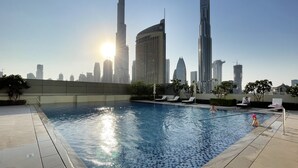 Una piscina con un horizonte urbano al fondo, incluyendo el Burj Khalifa.