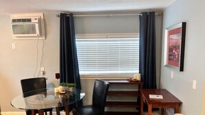 A compact living space with a dining area, a glass table, and a window with blinds. - Walla Walla Downtown Getaway (Walla Walla)