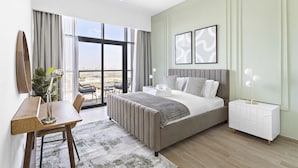 A modern bedroom with a large bed, bedside tables, a desk, and a view through large windows. - Silkhaus Burj Khalifa Area Extra Single Room (Dubai)