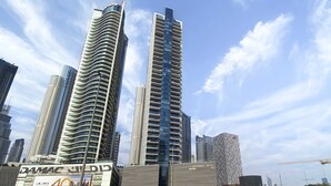 A modern high-rise building with a curved facade, a prominent sign for DAMAC Properties, and a clear sky. - Silkhaus Burj Khalifa Area Extra Single Room (Dubai)