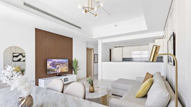 A modern living room with a flat-screen TV, a dining table, and a sofa. - Silkhaus Burj Khalifa Area Extra Single Room (Dubai)