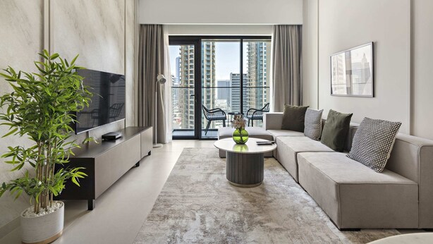 A modern living room with a sofa, a coffee table, a TV, and a potted plant. - Silkhaus Elegant Downtown Premium Tower w Pool (Dubai)
