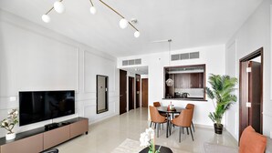 Un salon moderne doté d’un téléviseur à écran plat, d’un coin repas avec des chaises, d’un canapé et d’une plante en pot.
