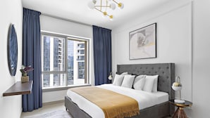 Ein modernes Schlafzimmer mit einem großen Bett, einem Nachttisch, einem Fenster mit Vorhängen und Blick auf die Stadt.