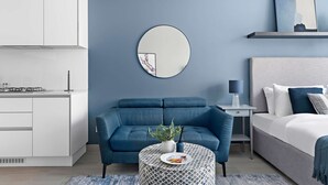 A modern bedroom with a bed, bedside table, and a round mirror on the wall. - Silkhaus New Large Furnished Studio in Luma21 (Dubai)