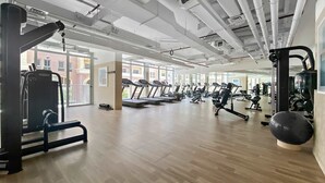 A spacious gym with treadmills, weight machines, and free weights. - Silkhaus New Large Furnished Studio in Luma21 (Dubai)