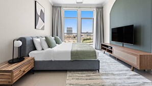 Een moderne slaapkamer met een groot bed, een televisie en uitzicht op de stad.