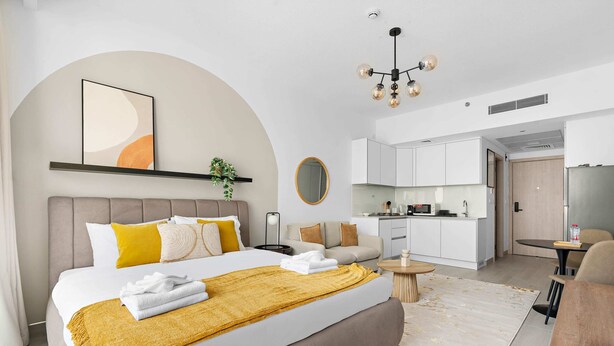 Ein modernes Hotelzimmer mit einem großen Bett, einer kleinen Küchenzeile und einem Esstisch.