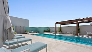Ein Poolbereich auf dem Dach mit Liegestühlen und einer Pergola.