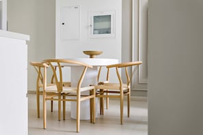 Un comedor con una mesa redonda y cuatro sillas de madera con asientos de fibras trenzadas.