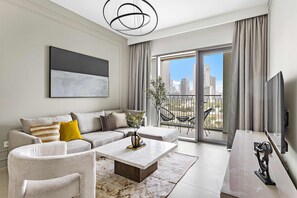 Una sala moderna con un sofá, una mesa de centro y un amplio ventanal con vista a la ciudad.
