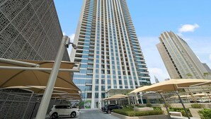 A tall modern building with a grid-like facade and a central entrance. - Silkhaus Luxurious New Tower With Pool Gym (Dubai)