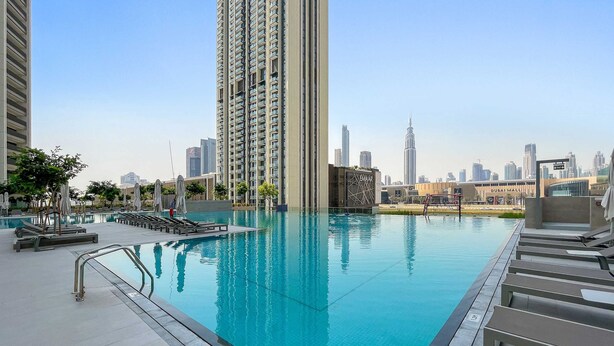 A rooftop pool with lounge chairs and a city skyline in the background. - Silkhaus Luxurious New Tower With Pool Gym (Dubai)